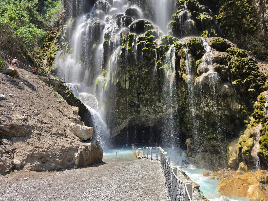 Cascadă și intrarea într-o peșteră mare deschisă