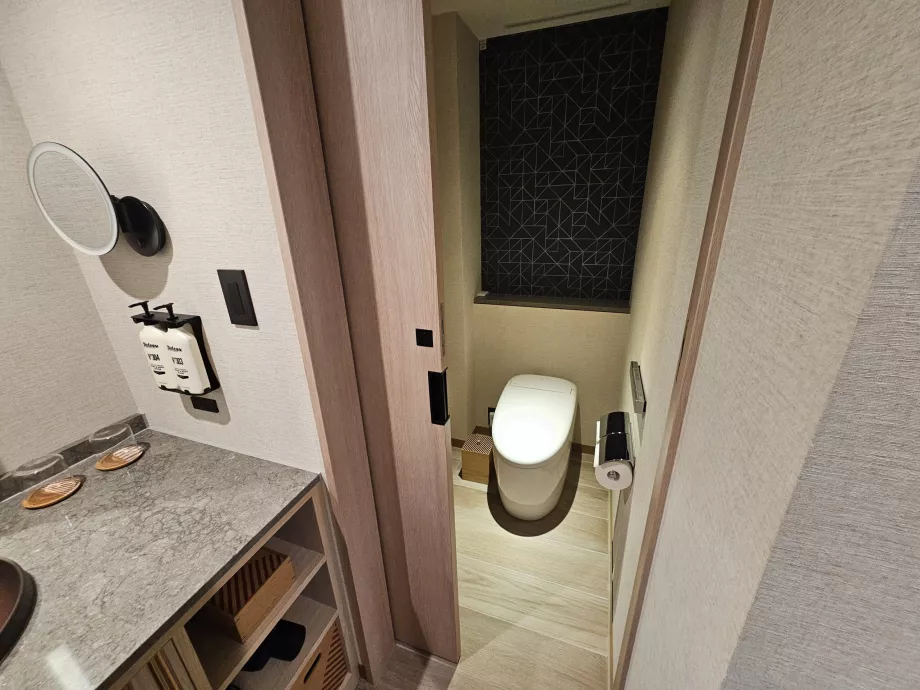 Toaletă separată de restul băii de o ușă